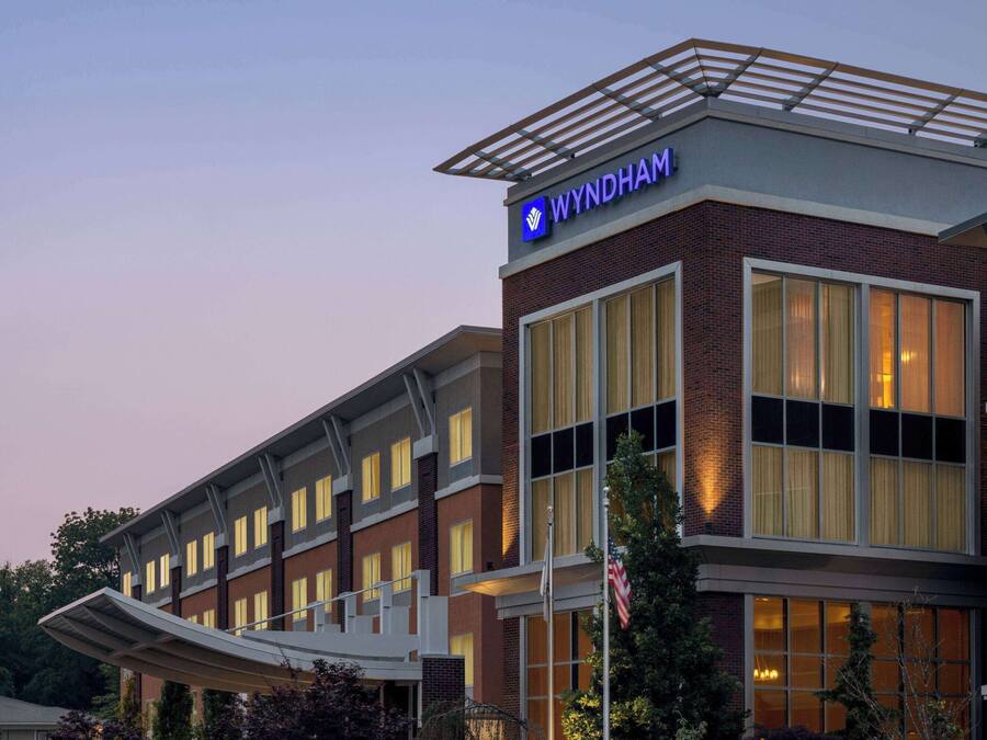 A Wyndham hotel with a modern design, featuring a prominent sign and a covered walkway.