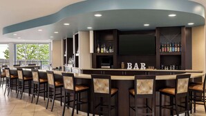 A bar area with a curved counter, multiple bar stools, and a television screen.