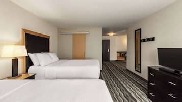 A hotel room with two beds, a TV, a dresser, and a bathroom visible in the background.