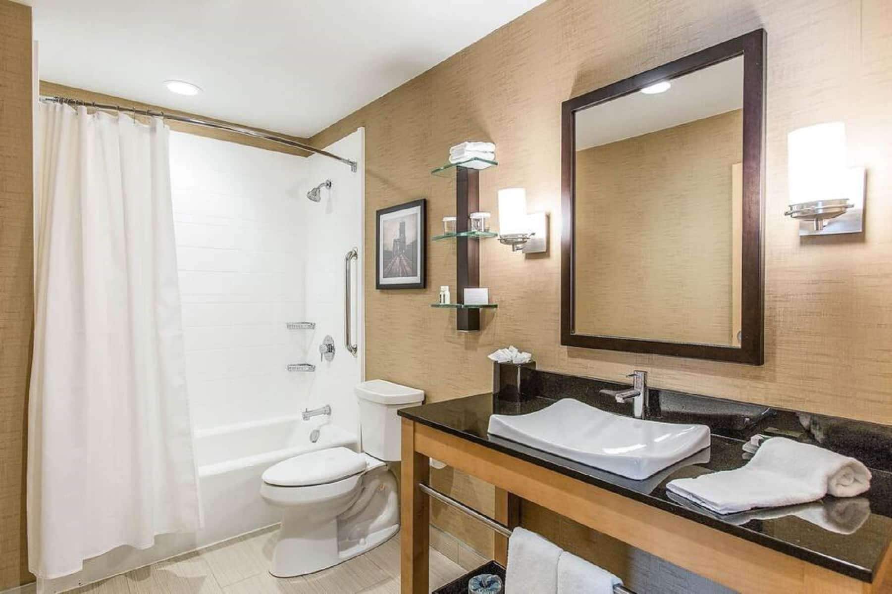 A modern bathroom with a bathtub, toilet, and a large mirror above the sink.