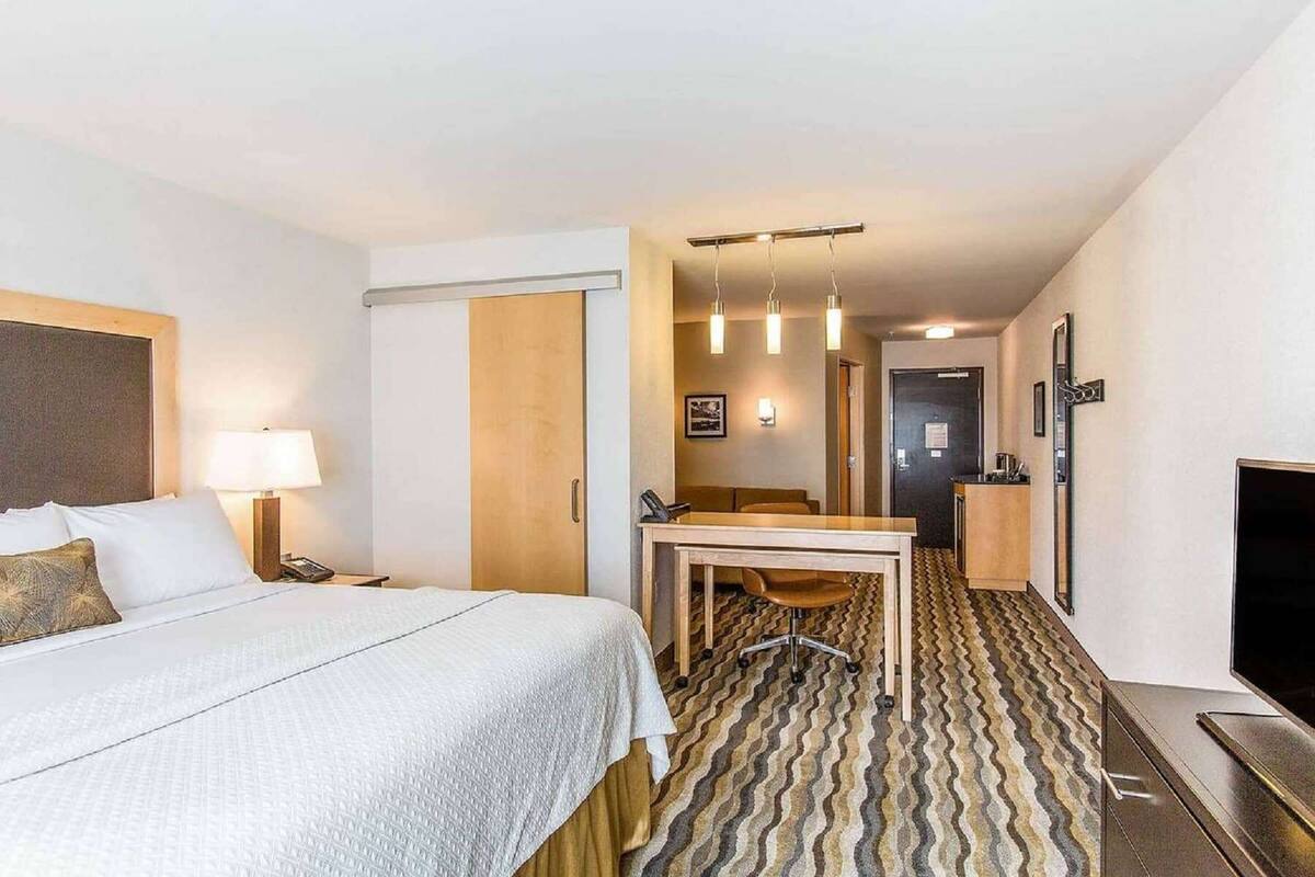 A hotel room with a bed, desk, chair, and television.