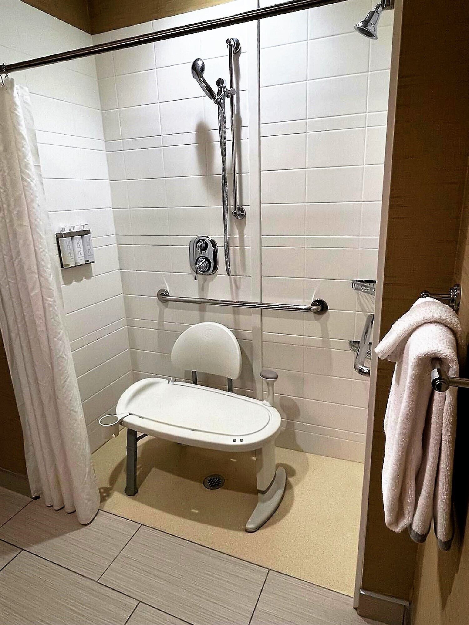Un bagno moderno con doccia a filo pavimento, un water e un porta asciugamani.