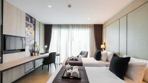 Hotellihuone, jossa on sänky, työpöytä, televisio ja suuri ikkuna, jossa on verhot.