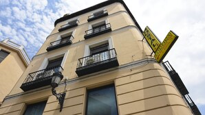 A building with multiple balconies, large windows, and a sign indicating a restaurant. - Hostal Edreira (Madrid)