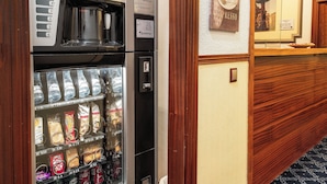 A coffee vending machine with a coffee cup display and a selection of coffee pods. - Hostal Edreira (Madrid)