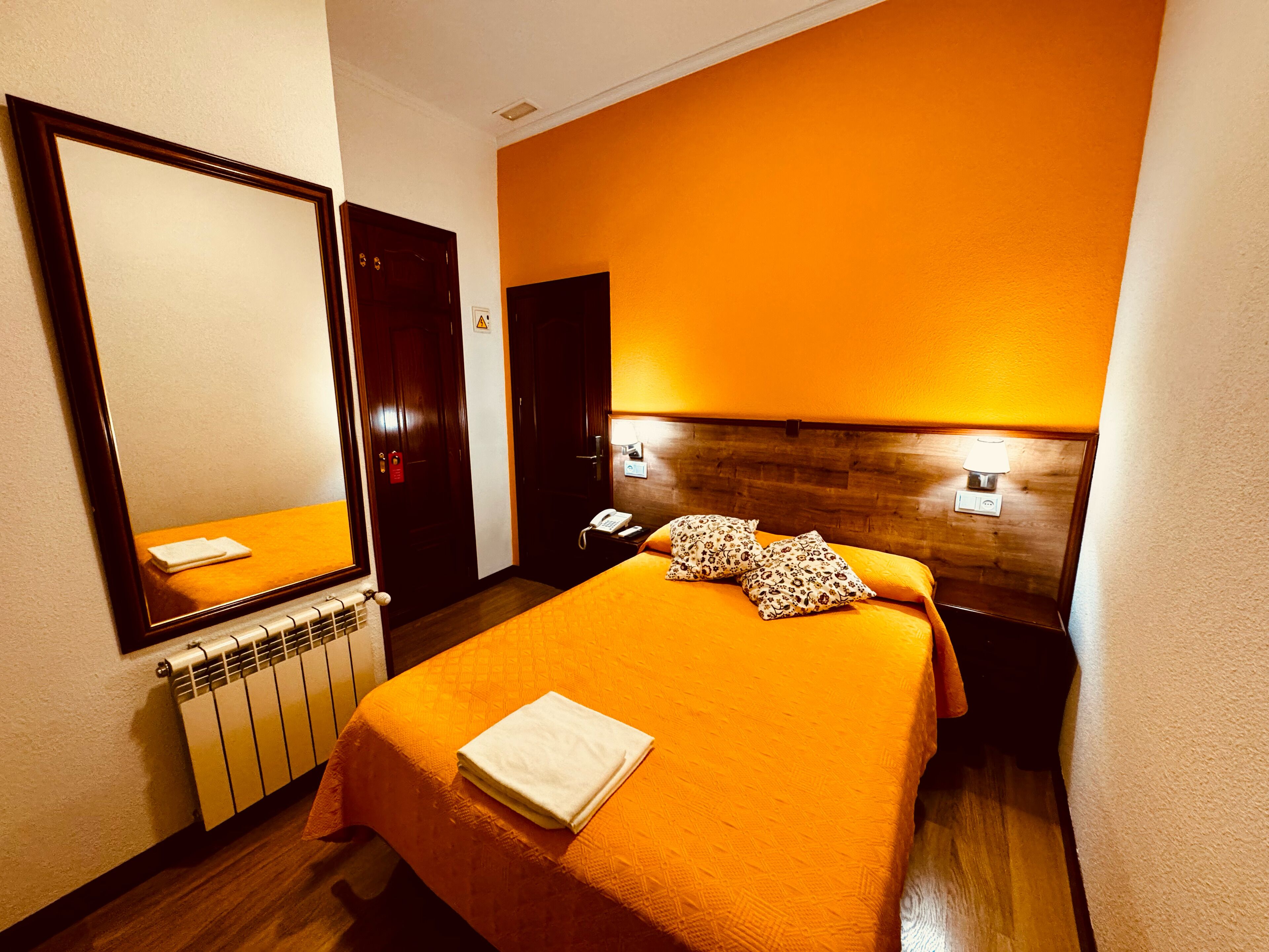 Een hotelkamer met een groot bed, een houten hoofdbord, een bedlampje en een telefoon.