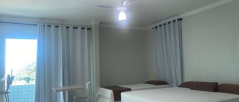 Una habitación de hotel con cama, escritorio, silla y ventilador de techo.