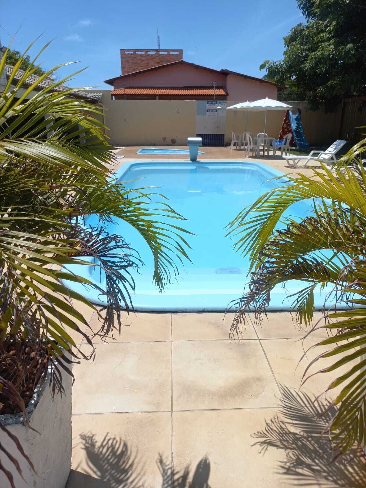 Una piscina con sillones de descanso y un edificio al fondo.