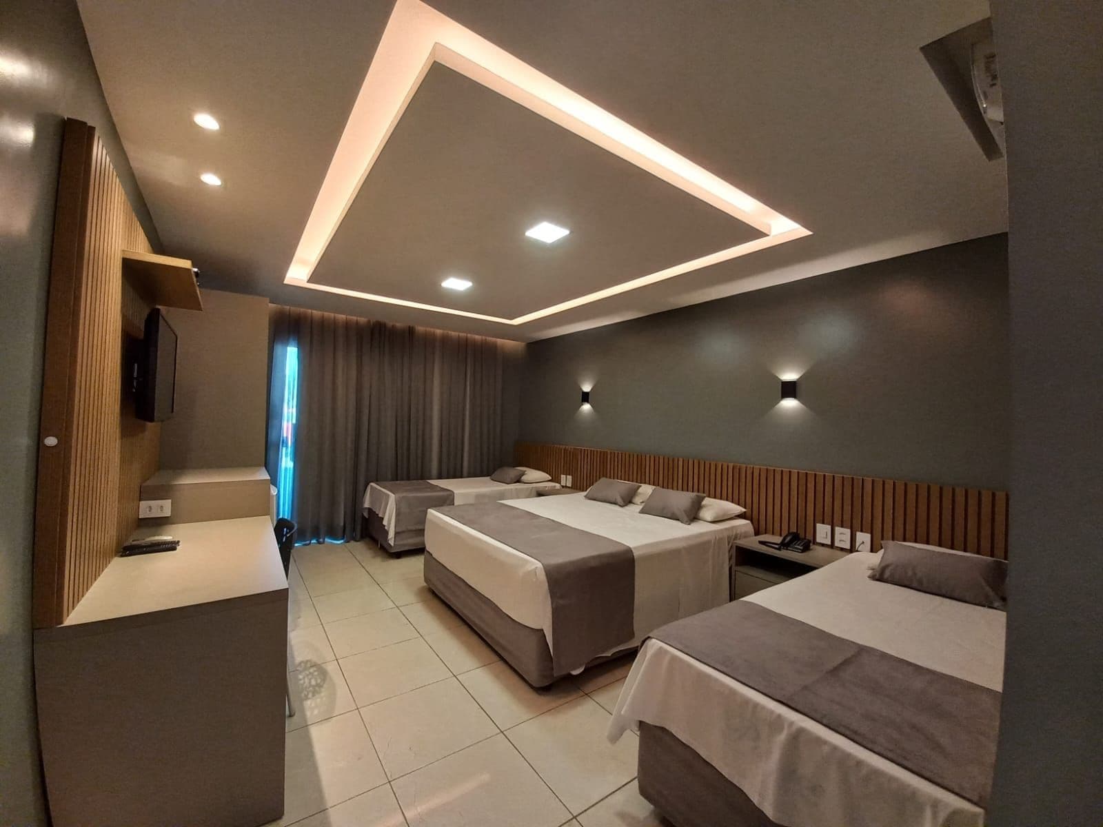 Una habitación de hotel moderna con dos camas, un escritorio y una televisión.