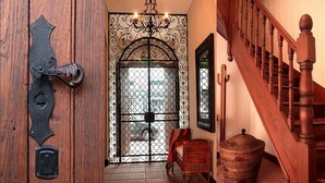 Una porta di legno con cancello in metallo, una sedia in vimini, un cesto intrecciato e una scala in legno.