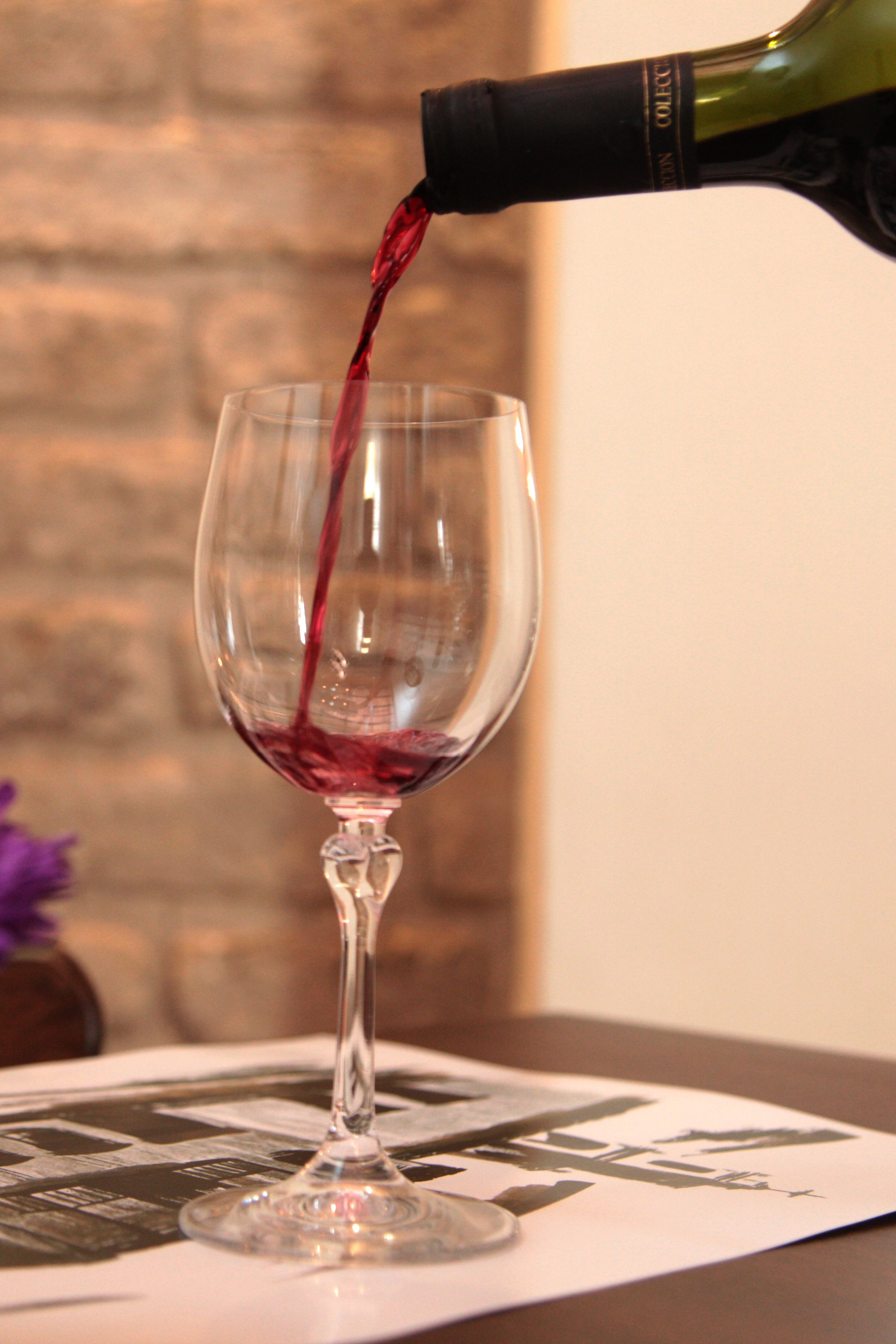 A wine glass being filled with red wine.
