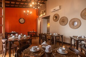 Un restaurante con mesas y sillas de madera, un reloj en la pared y platos decorativos.