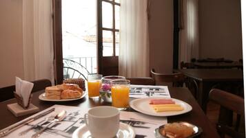 Ein Frühstückstisch mit Croissants, Schinken, Käse und Orangensaft.