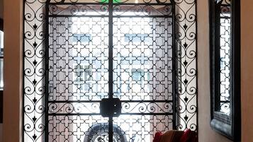 A room with a large decorative metal gate, a bench, and a chandelier.