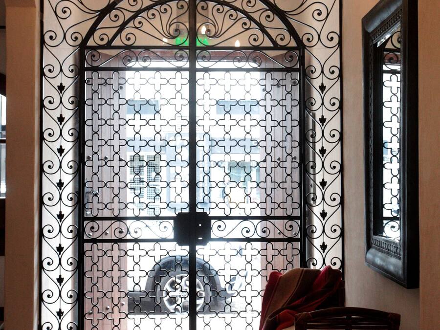 A room with a large decorative metal gate, a bench, and a chandelier.