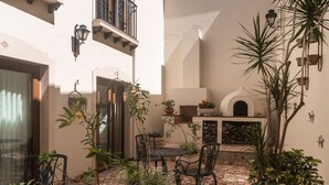 Un cortile con pavimento in mattoni, piante in vaso, mobili da esterno e un camino.