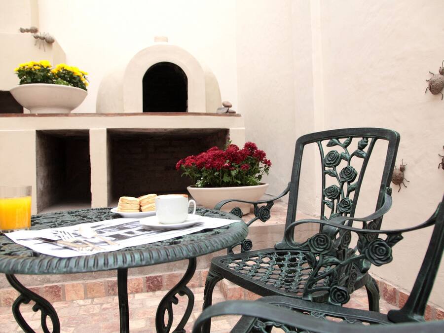 Eine Terrasse mit Esstisch, Stuhl, Blumentopf und dekorativer Wand.