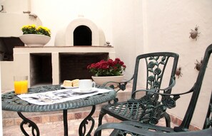 Eine Terrasse mit Esstisch, Stuhl, Blumentopf und dekorativer Wand.