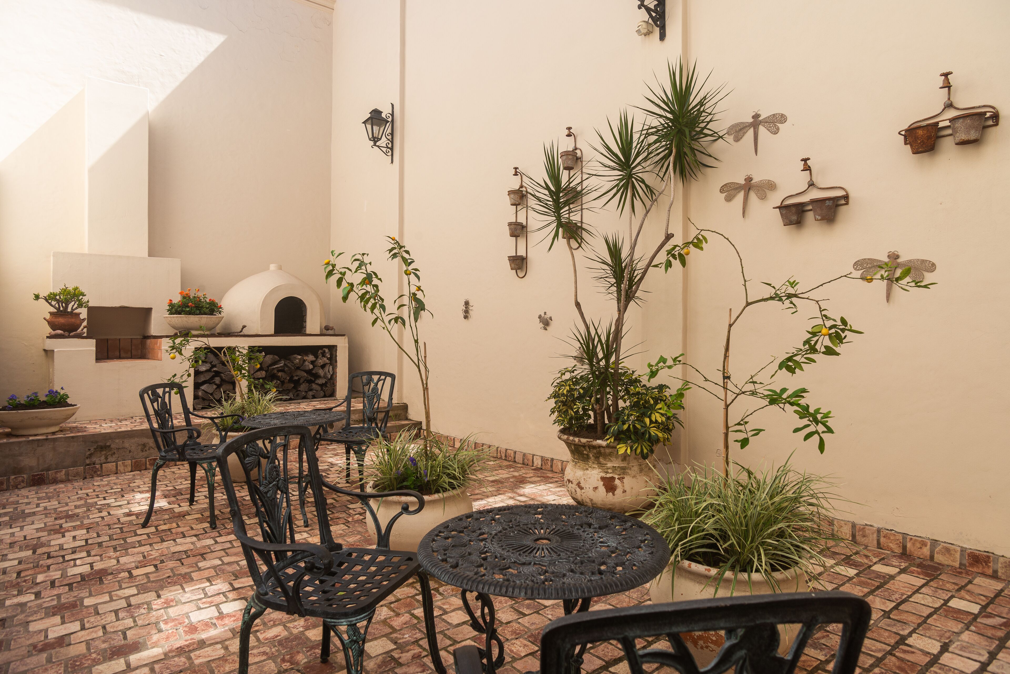 A patio with brick flooring, outdoor seating, a white oven, and various potted plants.