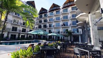 Une cour d’hôtel avec des espaces de détente en plein air, une piscine et plusieurs balcons.