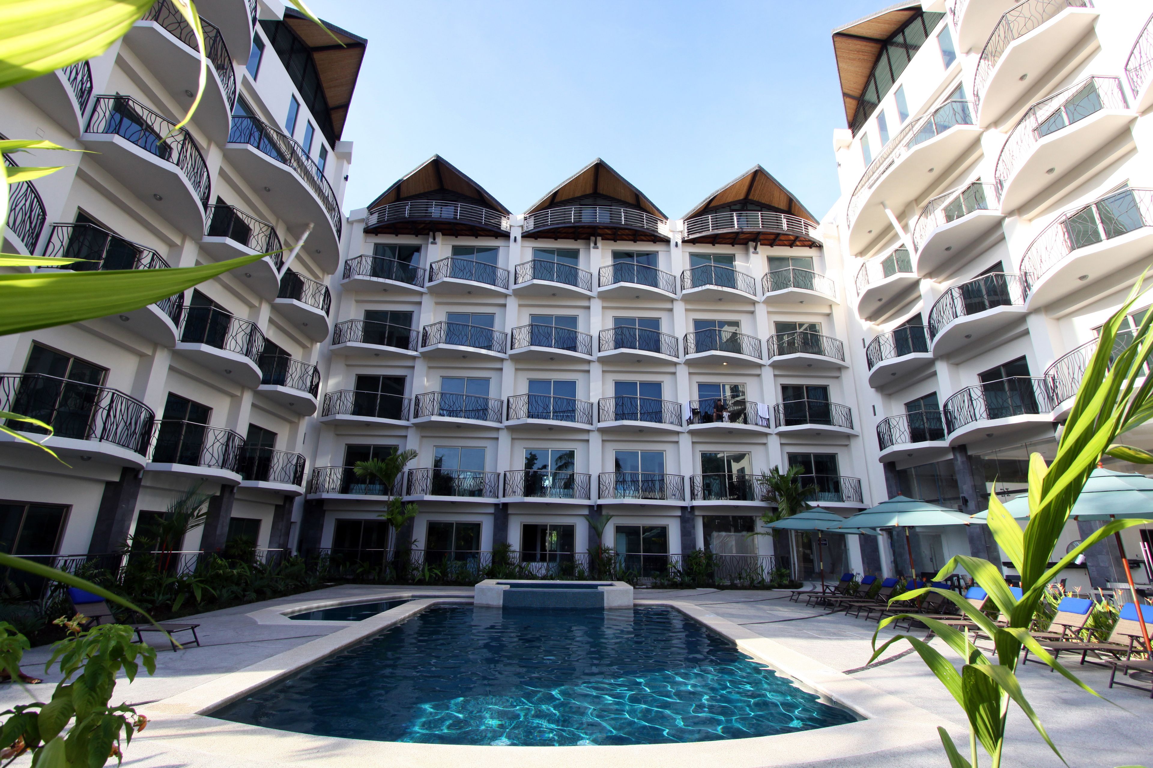 Un hôtel à plusieurs étages doté de balcons, d’une piscine et d’espaces de détente en plein air.