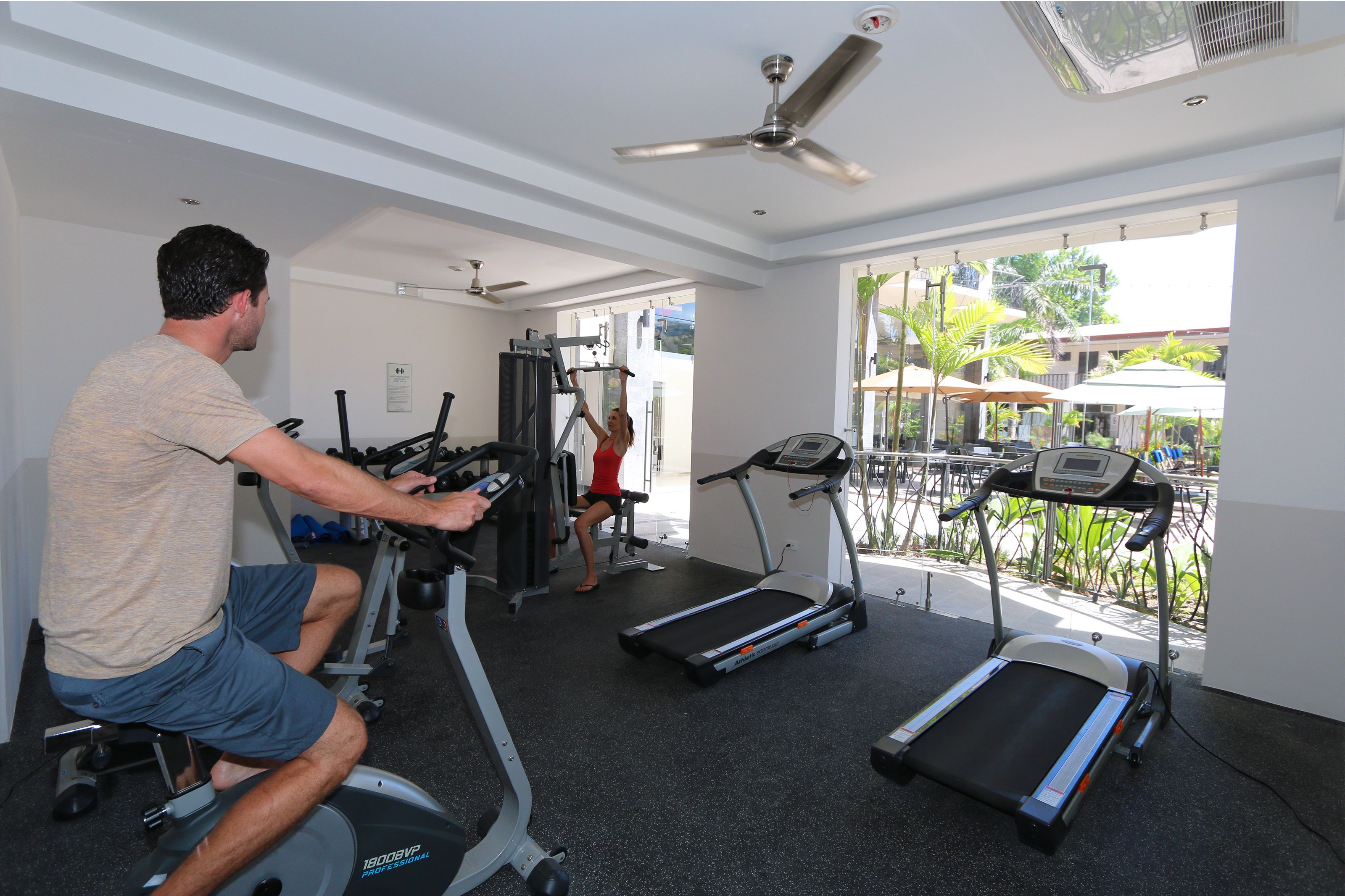 Une salle de sport équipée de tapis de course, d’un vélo d’appartement et d’une machine de musculation.