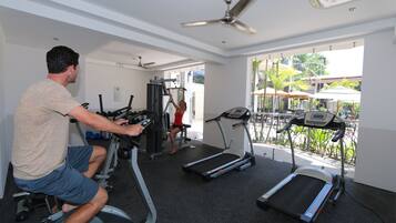 Une salle de sport équipée de tapis de course, d’un vélo d’appartement et d’une machine de musculation.
