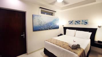 Una habitación de hotel con una cama, un ventilador de techo, una ventana y obras de arte en la pared.
