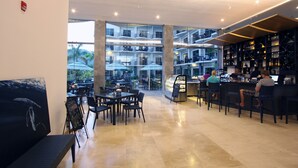 A modern hotel lobby with a glass-enclosed dining area, multiple floors visible through the glass, and a bar area with patrons.