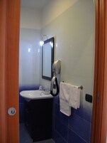 Baño con lavamanos, espejo, perchero y secador de manos.
