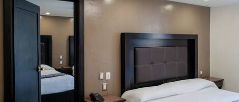 Habitación de hotel con una cama grande, una mesita de noche con teléfono, una lámpara y un espejo.