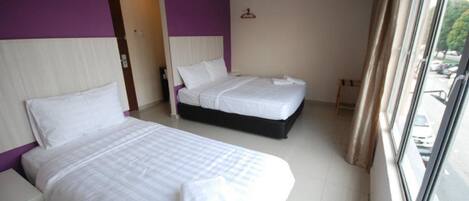 A hotel room with two beds, a window with curtains, and a view of the outside.
