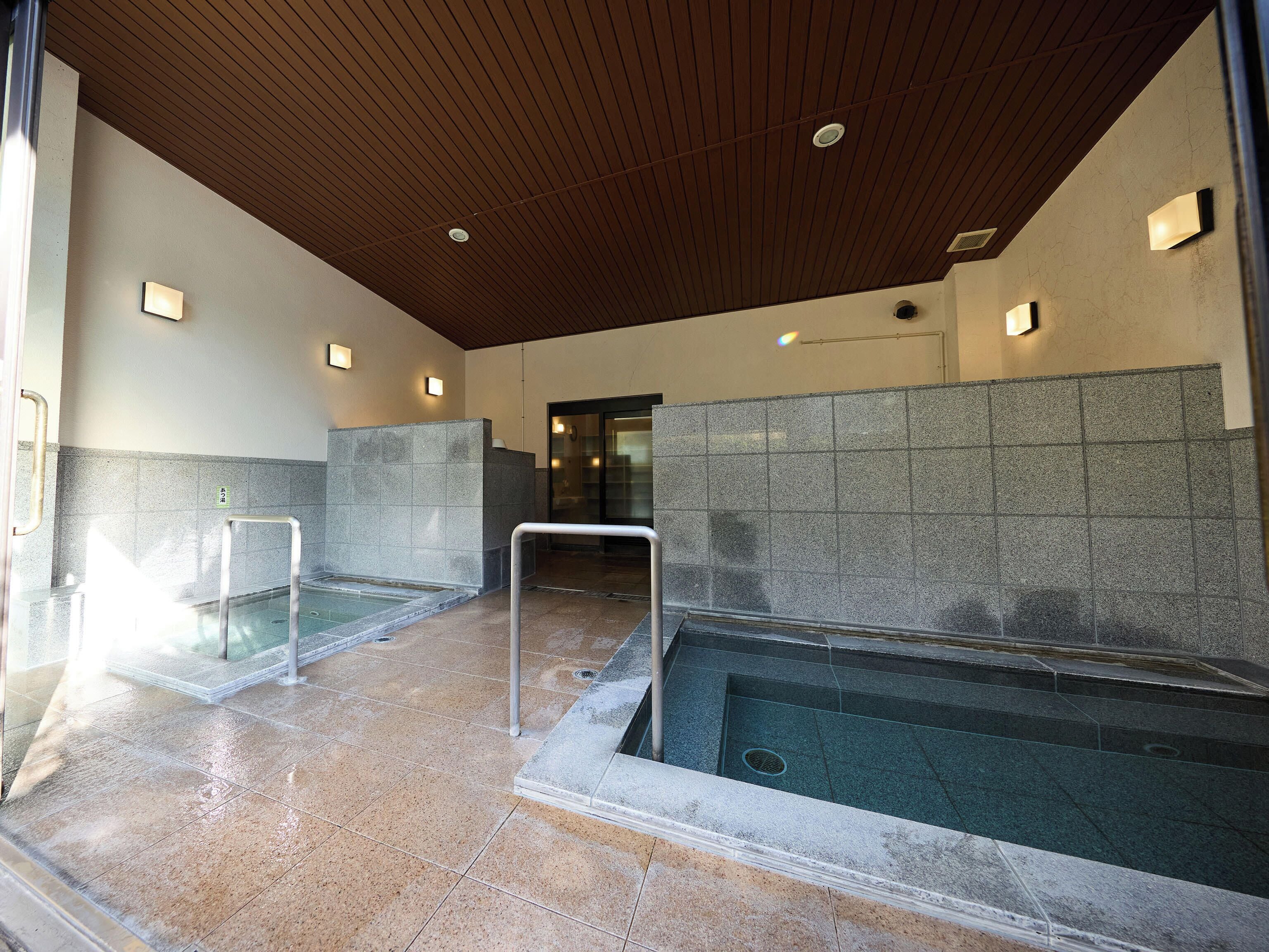 A modern indoor pool area with clear water, tiled walls, and a wooden ceiling.