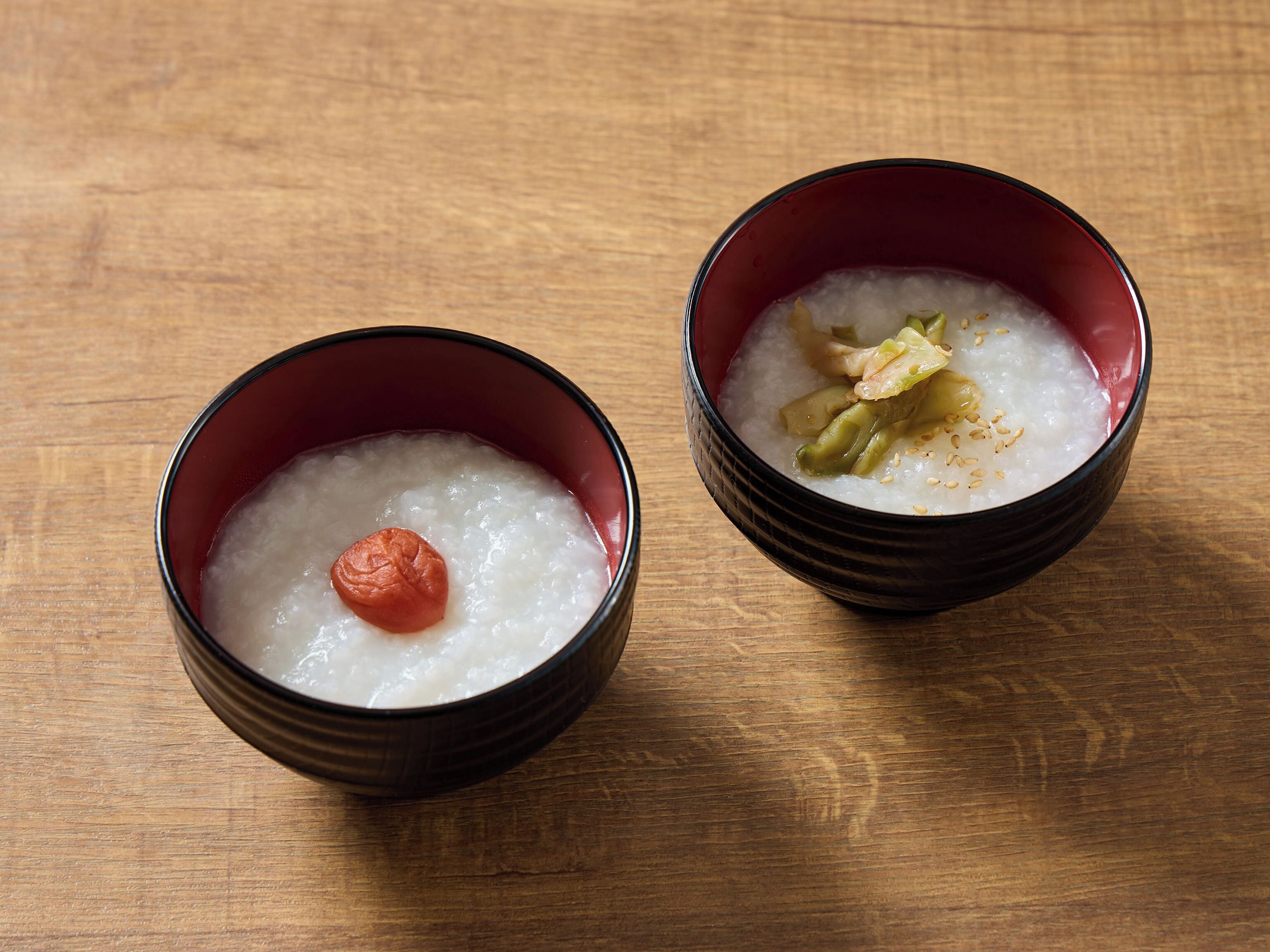 Two bowls of rice porridge on a wooden table.