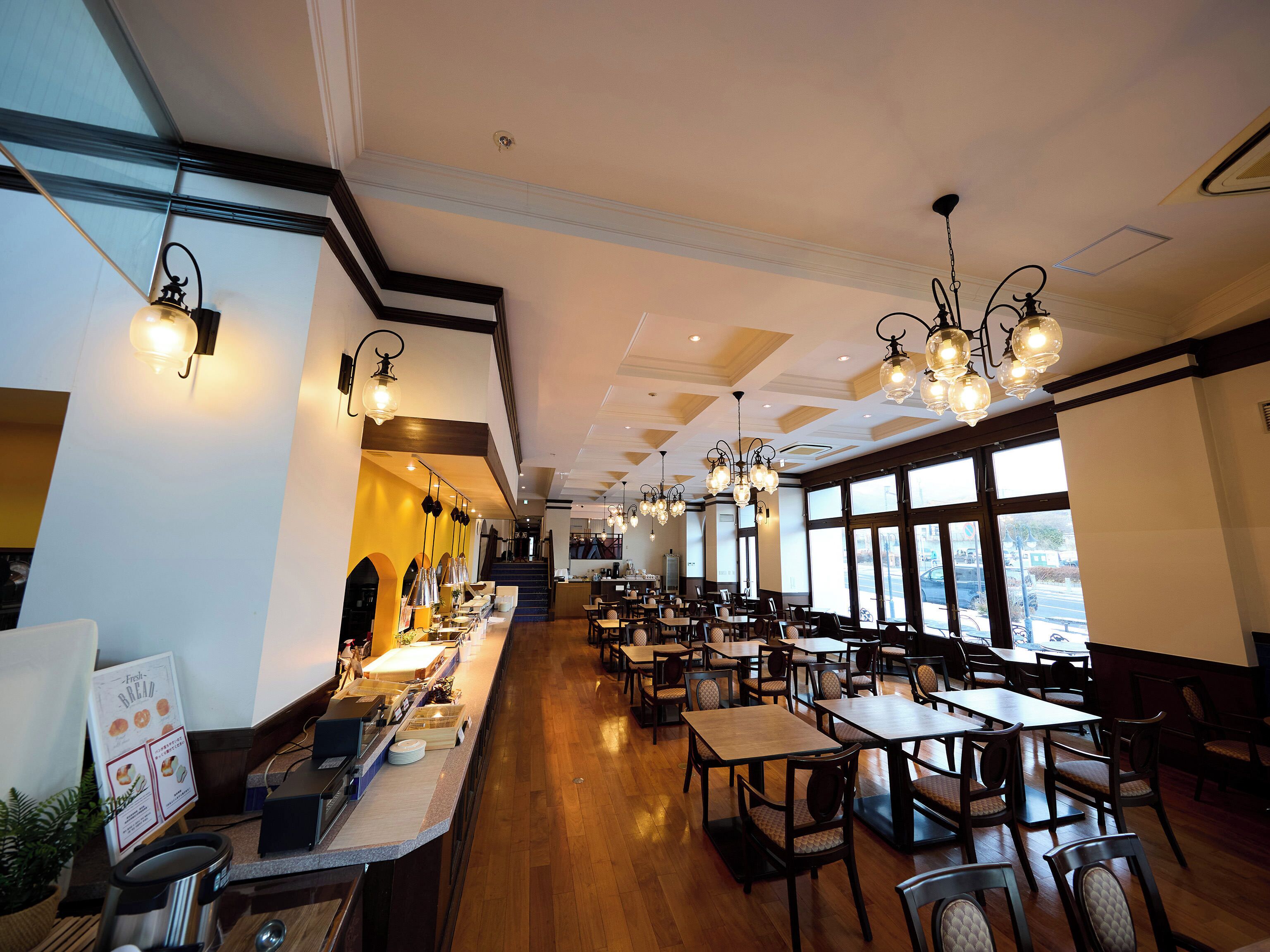 A spacious restaurant with high ceilings, modern lighting, and large windows offering views.