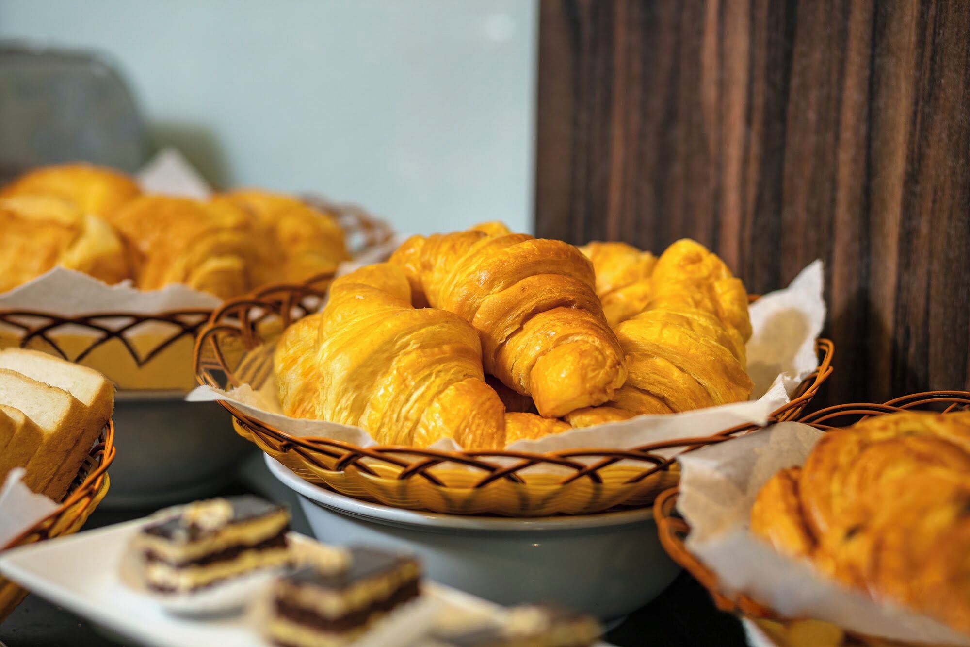 Un cestino di croissant dorate e un piatto di pane a fette.