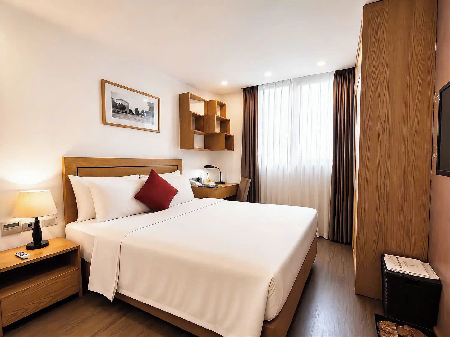 Ein Hotelzimmer mit Bett, Nachttisch, Lampe und einem gerahmten Bild an der Wand.