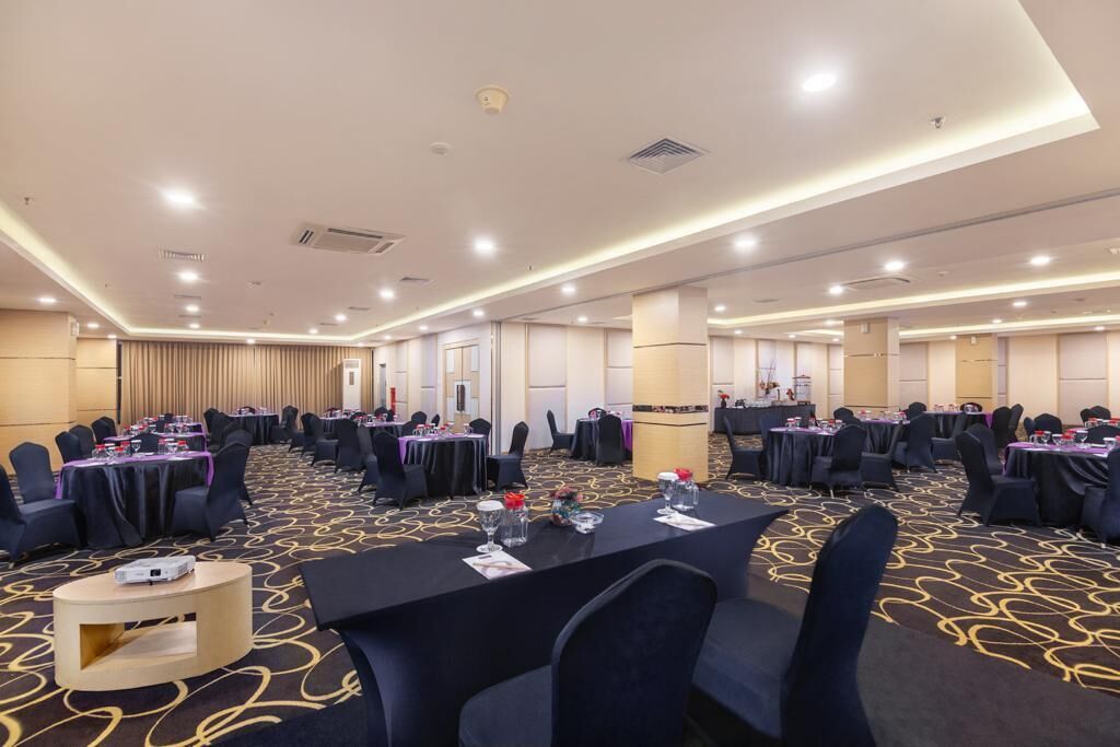 A conference room with round tables, chairs, and a carpeted floor.
