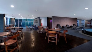 Un comedor interior moderno con mesas y sillas de madera, mesa de billar y vista al exterior.