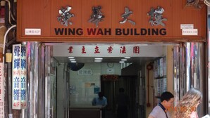 Exterior do Edifício Wing Wah com placa indicando seu nome e endereço.