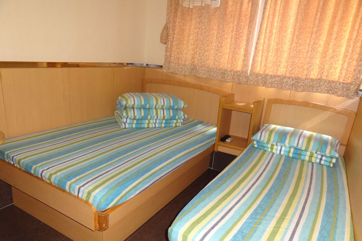 A small, cozy room with two single beds, each with striped bedding.