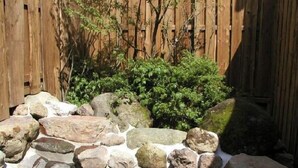 Una fuente de piedra con rocas y una valla de madera al fondo.