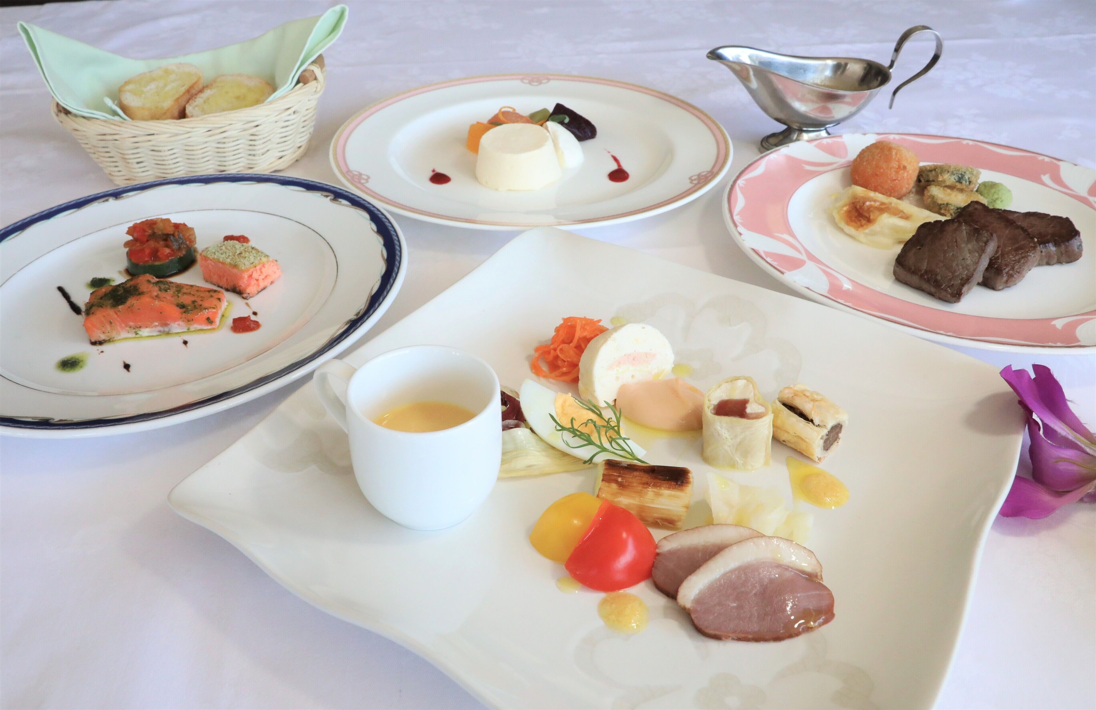Ein Tisch mit verschiedenen Speisen, darunter Lachs, Eier und Fleisch, dazu Brot und eine kleine Schale Soße.