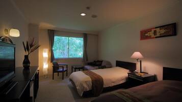 Ein Hotelzimmer mit Bett, Schreibtisch, Stuhl, Fernseher und einem Fenster mit Vorhängen.