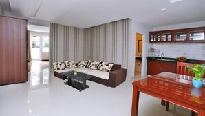 A modern living room with a sofa, a glass coffee table, and a wooden dining table. - White Swan Apartment (Nha Trang)