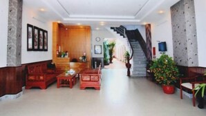 A spacious lobby with a staircase, wooden furniture, and potted plants. - White Swan Apartment (Nha Trang)