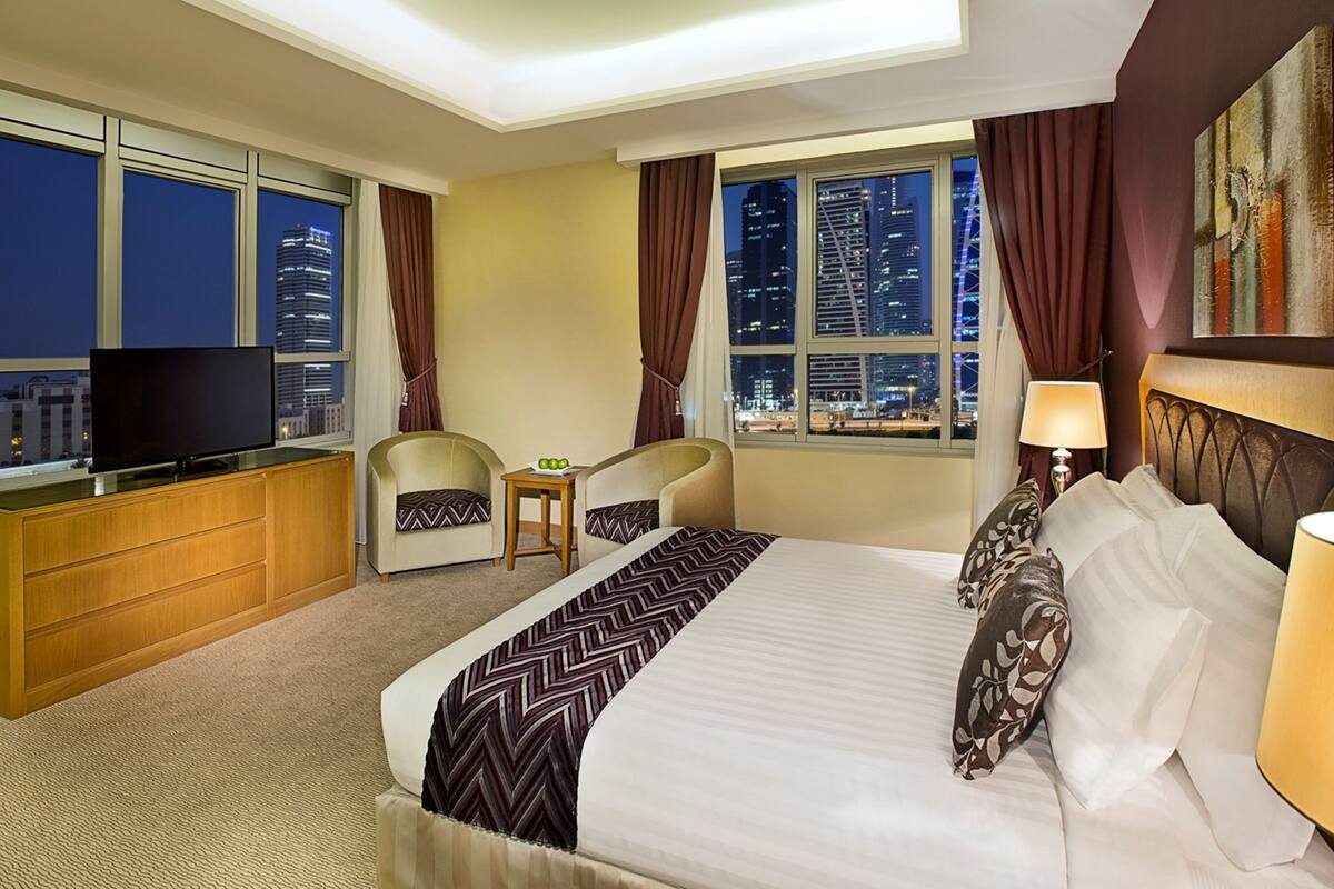 A hotel room with a bed, a TV, a desk, and two chairs.