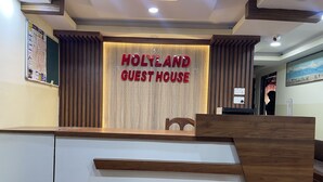 Een receptiebalie met een bord waarop staat: HOLYLAND GUEST HOUSE.