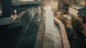 A covered outdoor seating area with a pool, overlooking a landscape with hills and a thatched-roof structure. - Samanvaya - Adults Only (Sidemen)