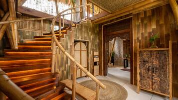 Una escalera de madera con diseño en espiral que conduce a una habitación con decoración tradicional y un gran armario de madera.